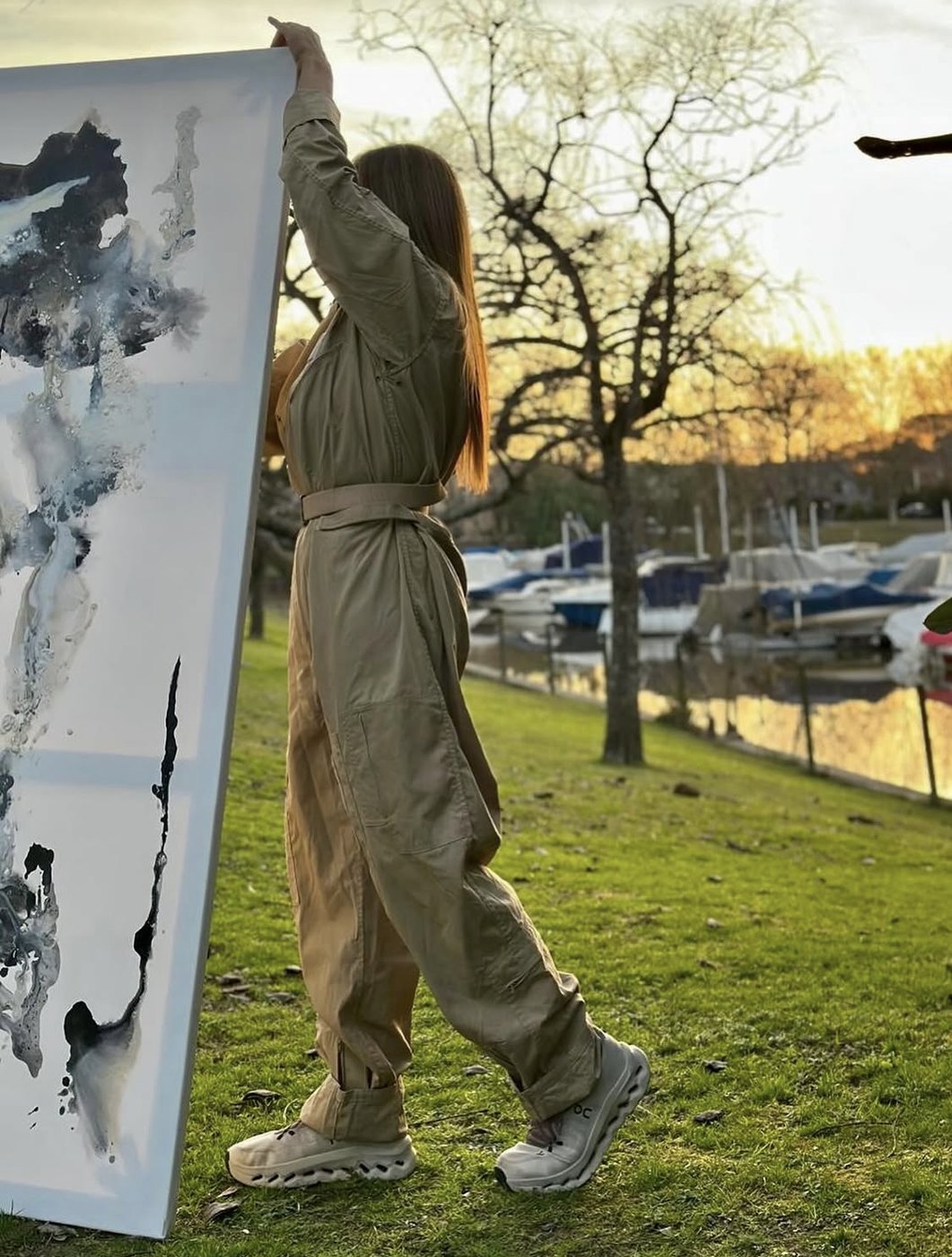 Marcela Batistic sosteniendo una obra junto al río al atardecer